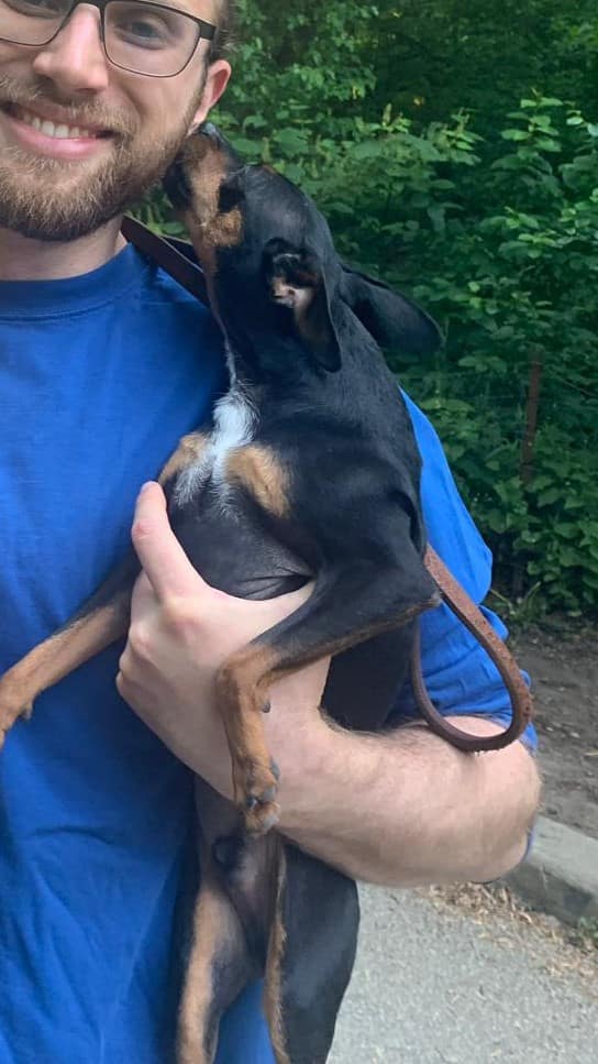Mellow Vibes Dog Training's Daniel cuddling with a little pup outdoors